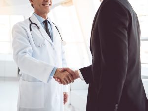 Healthcare compliance professionals shaking hands